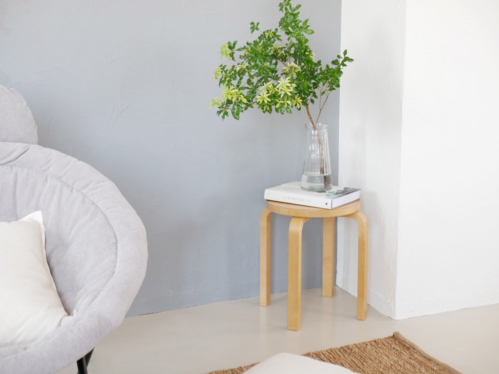 リビングルームに置かれたアルテック製スツール60。グレーのクッションやコーヒーテーブルと共に配置されています。