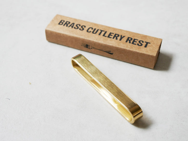 Horn Please製の真鍮カトラリーレスト。幅9cm、高さ1cmのシンプルなデザインがテーブル上に配置されている