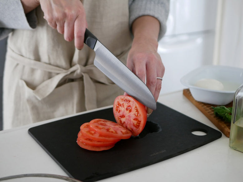 京セラのココチカルシリーズセラミックナイフが木製まな板と新鮮な野菜と共にキッチンに並んでいる