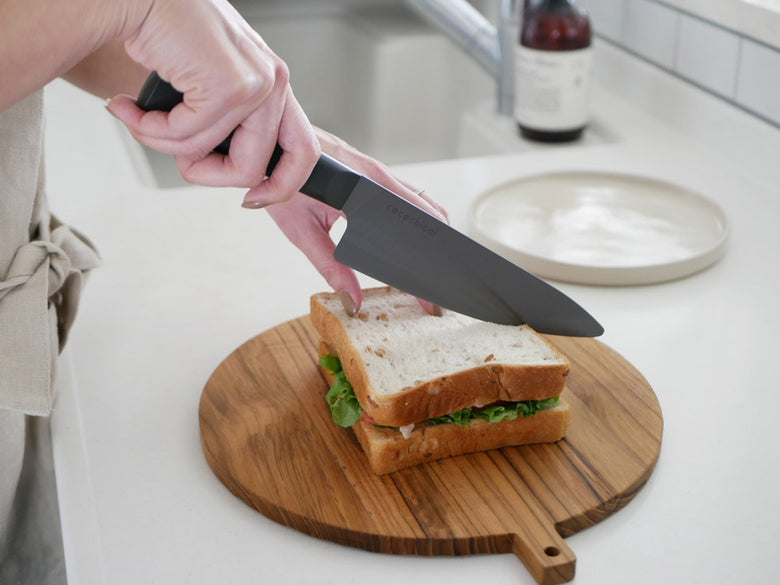 京セラココチカルのセラミックナイフが木製まな板に置かれ、新鮮な野菜と共に調理準備が整っているキッチン用品