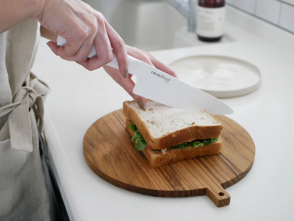 KYOCERA/京セラのココチカルナイフがまな板の上に置かれ、野菜や果物が食器に盛られたキッチン用品の配置