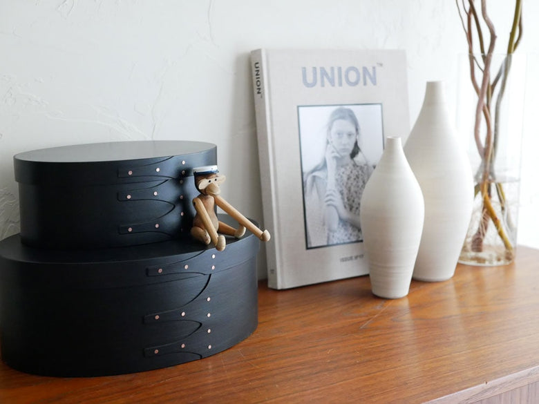 カイ ボイスンのスチューデントキャップが無垢材の木製引き出しやチェスト、コーヒーテーブルとともに展示されている自然なインテリア写真