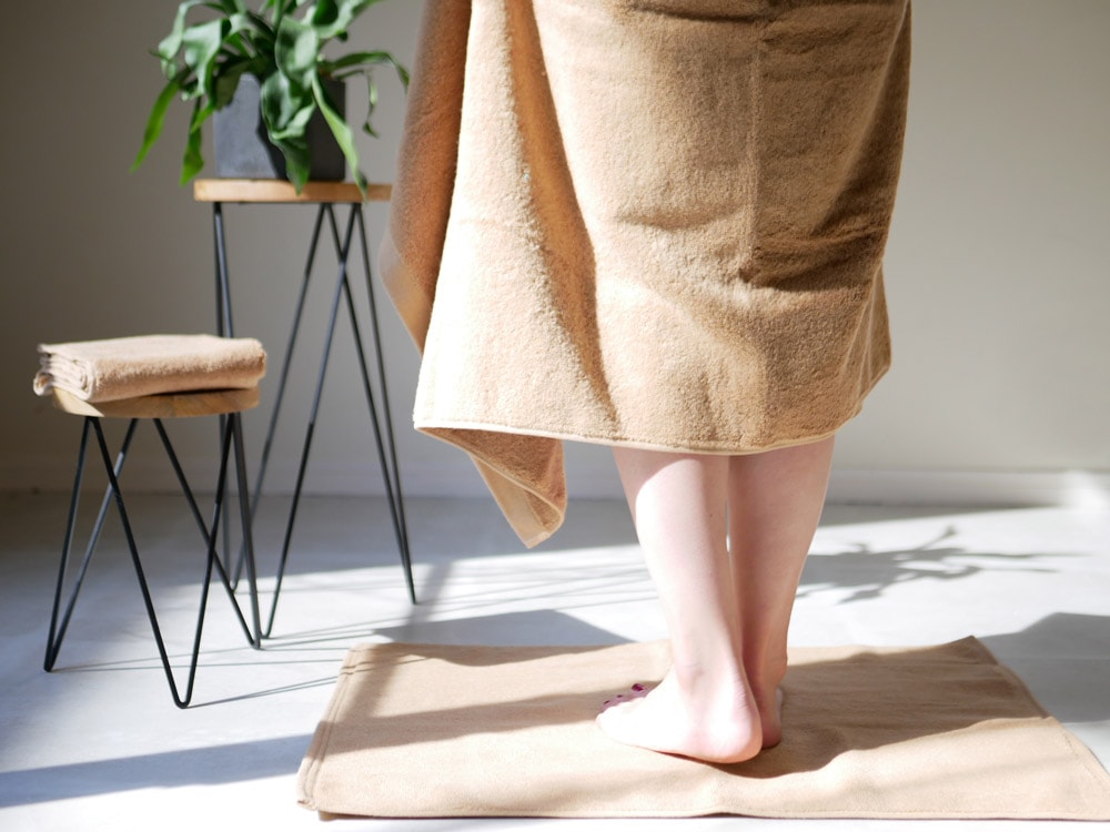 REST FOLKの綿100％プラシッドバスタオルが木製の床に敷かれた様子