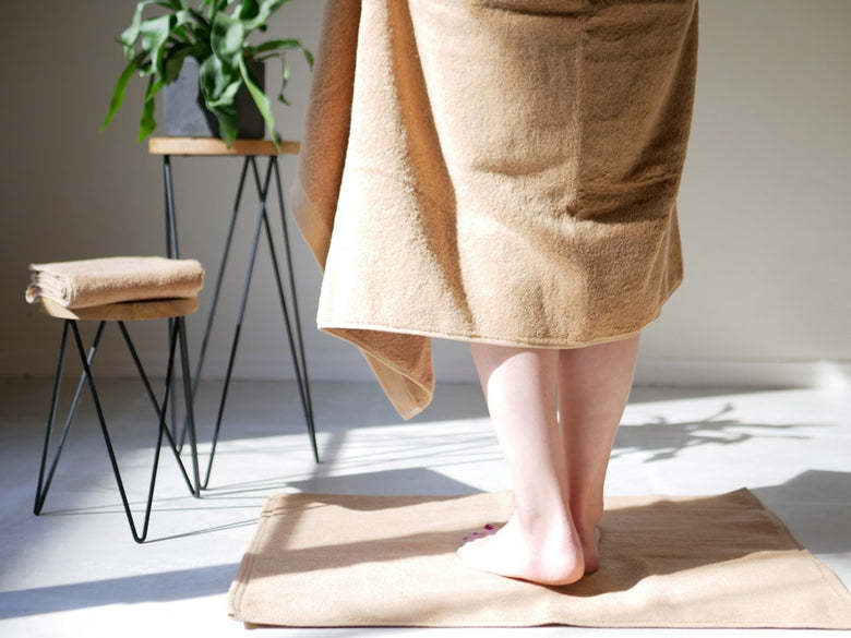 REST FOLKの綿100％プラシッドバスタオルが木製の床に敷かれた様子