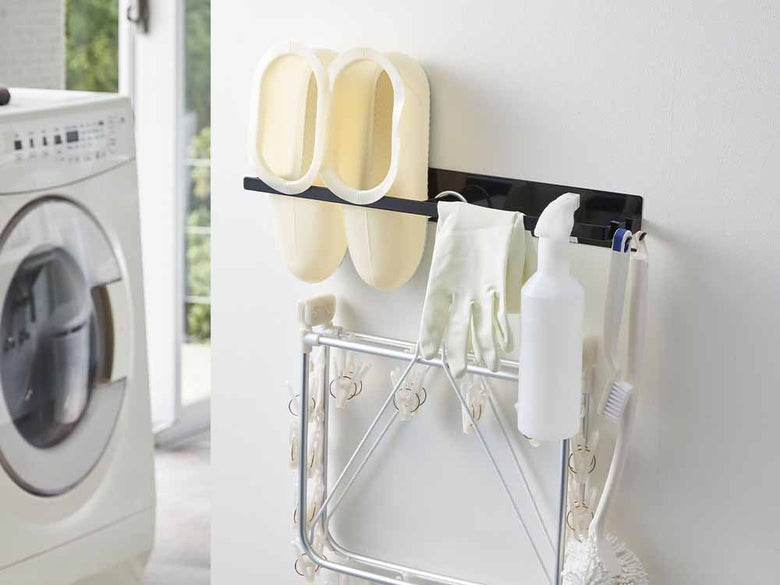 YAMAZAKIタワーのマグネット洗濯ハンガー収納ラック。スチール製の2段棚とマグネット付きフックが壁に取り付けられ、洗濯物を整理できる収納ソリューション