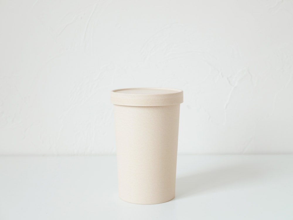 ホーンプリーズECOキャニスターのプラスチック製シリンダーと蓋、コーヒーカップスリーブが並べられたセット