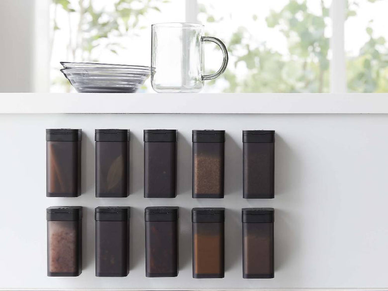 "棚に置かれた黒色マグネットスパイスボトルと観葉植物"