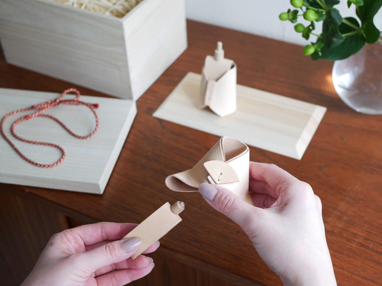 Comore Sunブランドのヌメ革製お雛様セット。お内裏様とお雛様がヒノキの台座に並んでいます