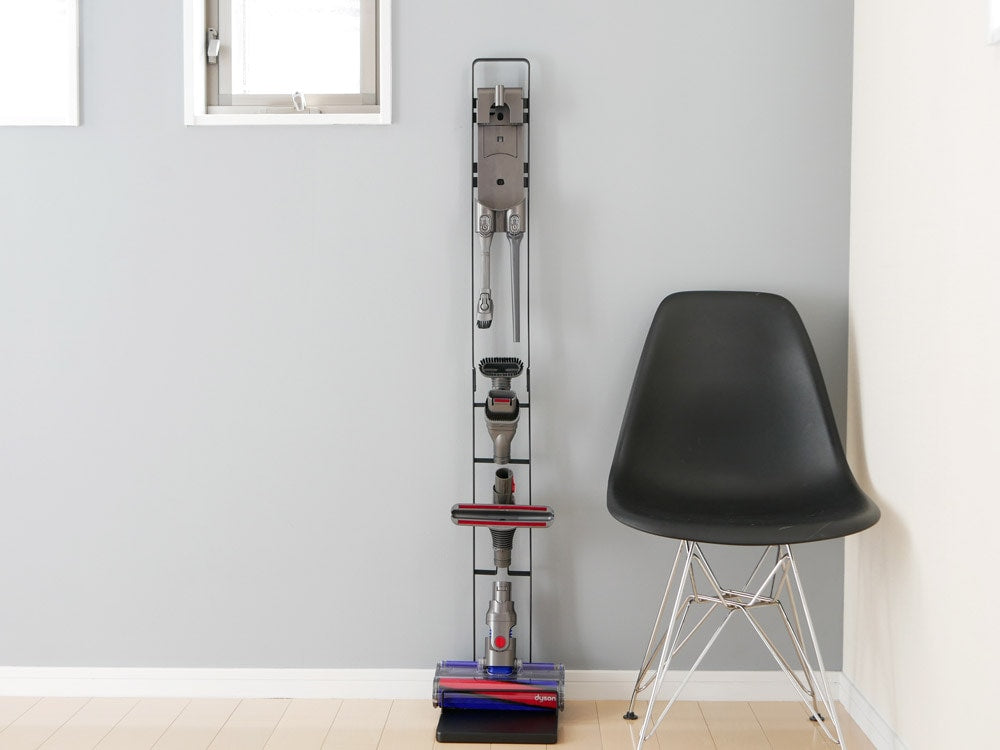 木製フローリングの床に設置されたtowerブランドのコードレスクリーナースタンド。スチール製で高さ127cm、ダイソンV6～V10シリーズ対応の壁掛けブラケット付き。