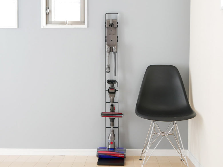 木製フローリングの床に設置されたtowerブランドのコードレスクリーナースタンド。スチール製で高さ127cm、ダイソンV6～V10シリーズ対応の壁掛けブラケット付き。