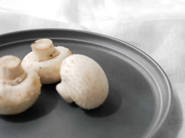 エンボスラインのキントーFOG磁器プレートにマッシュルームが配置された静物写真