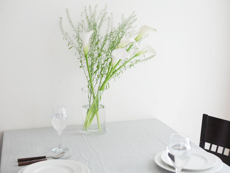 テーブルに花束を飾ったBOB CRAFT製円筒ベースのガラス花瓶