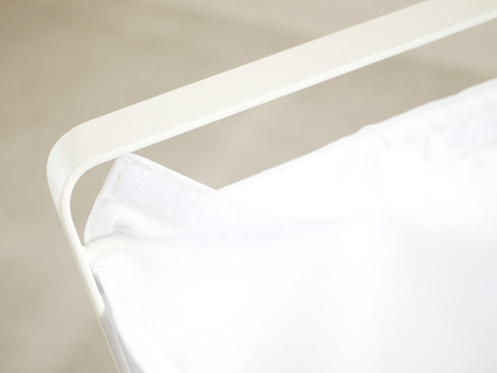 YAMAZAKIタワーの手荷物収納ボックスがベッドフレーム横に配置されており、スチールフレームとポリエステルバスケットで構成されている様子