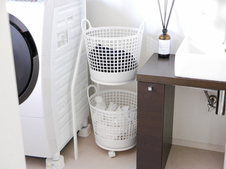 洗濯室に置かれた2段ランドリーバスケットと洗濯機