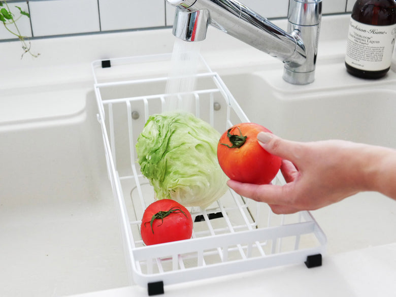 YAMAZAKIのタワー型伸縮水切りワイヤーバスケットがシンクに設置され、食器を整理している様子