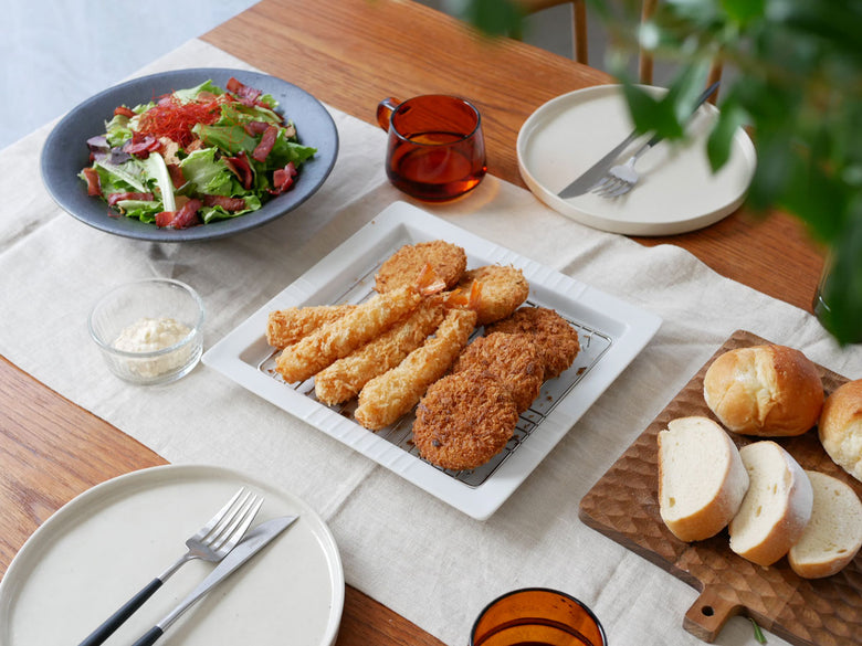 揚げ物を盛った日本製スクエア磁器皿と18-8ステンレス製アミのセットがテーブルに並べられている