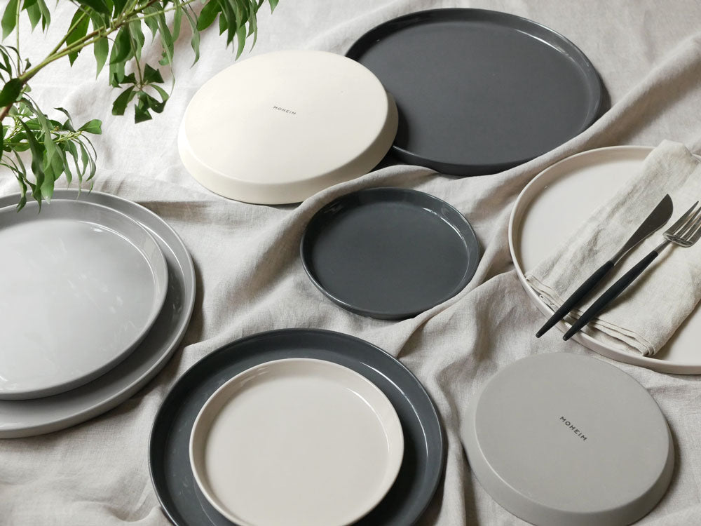 MOHEIM（モヘイム）の手作りセラミックディナウェアセット。サイズ260mm、210mm、150mmの各プレートがテーブルに並んでいます。