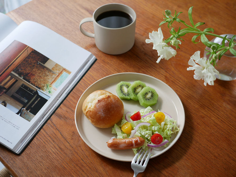 テーブル上にベトナム製の手作り陶器プレートに盛られた果物とパンが配置された食事シーン