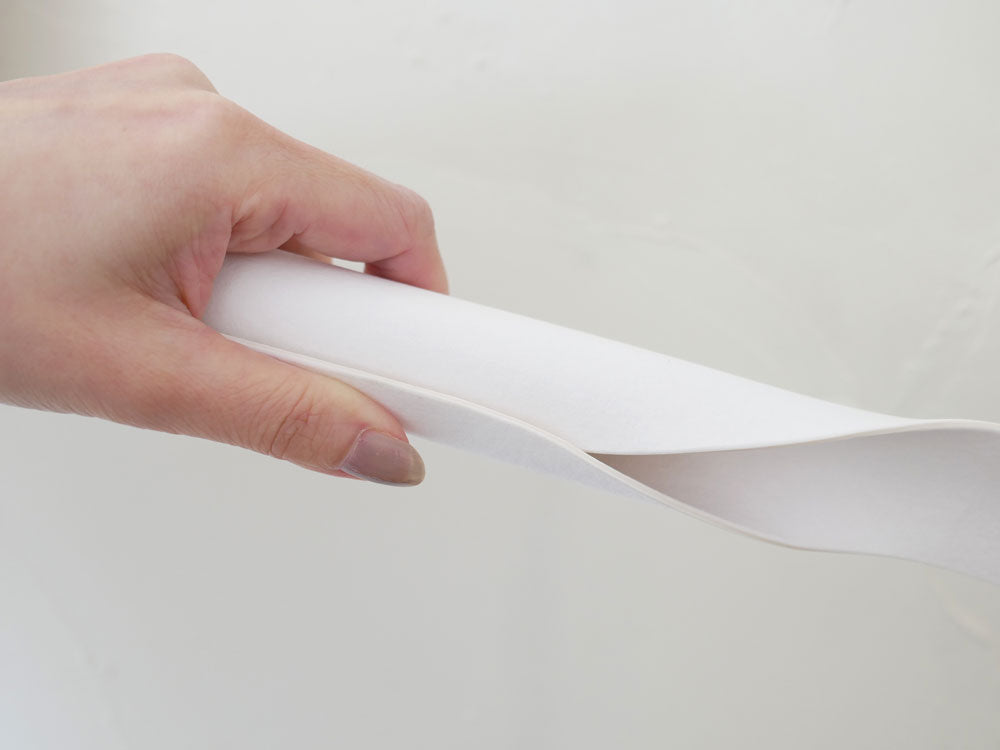 指と爪で操作されている紙やプラスチック製の文房具が写っている画像