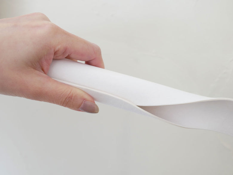 指と爪で操作されている紙やプラスチック製の文房具が写っている画像