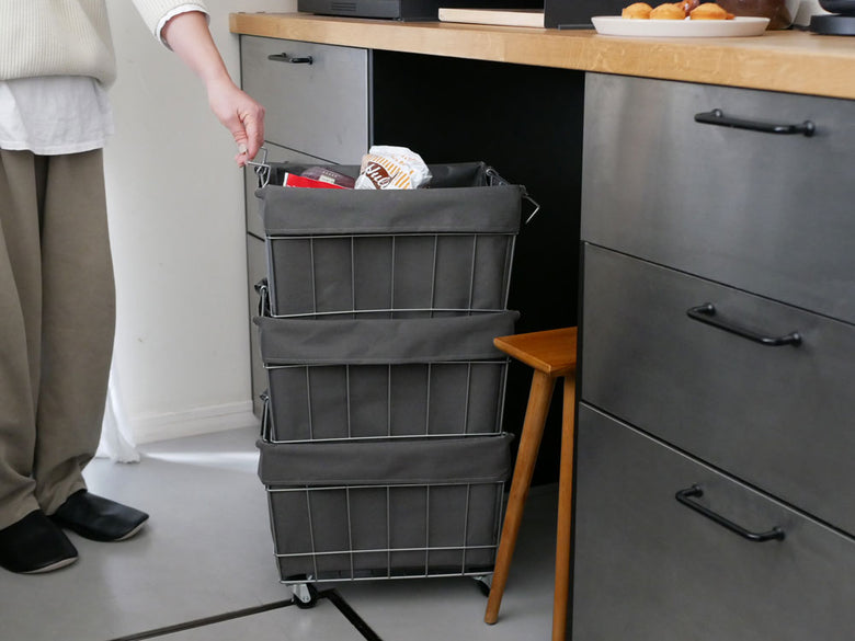 キャスター付きのグレー色のスタッキングバスケットがキャビネットや棚に配置されている様子