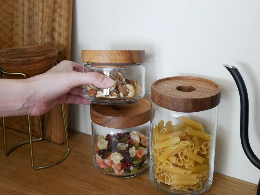 アカシア製の蓋を持つソーダガラスの食品保存用ジャーとロータスティーサーバーが棚に並べられたテーブルウェアセット