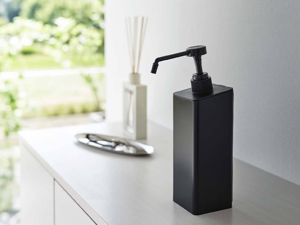 バスルームの洗面台カウンタートップにマグネット式アルコール除菌スプレーボトルや石鹸ディスペンサーが配置されている様子