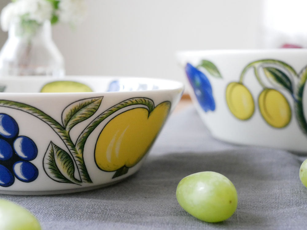 アラビアのパラティッシ磁器ボウルに盛られた果物と食器が並んだテーブルの写真