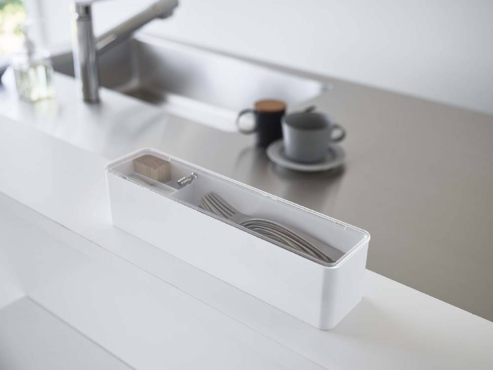 銀色の蓋付きカトラリーケースがキッチンのカウンタートップに設置され、シンクや家庭用電化製品と共に配置されている様子