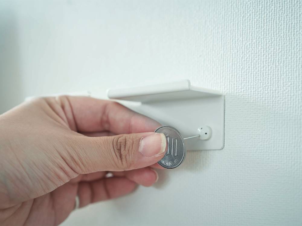 壁に取り付けられた【smart/スマート】ウォール スマートフォン&ヘッドホンホルダーに、スマートフォンとヘッドホンが掛けられている様子