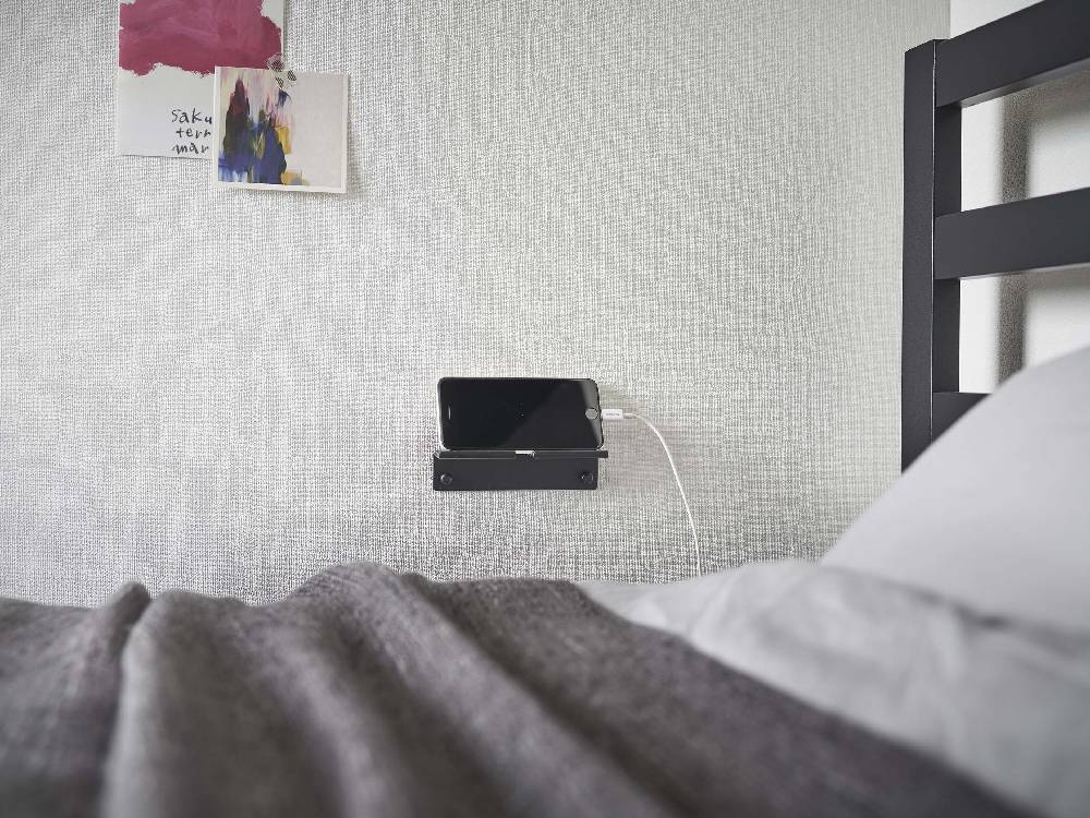 寝室の壁に取り付けられたシルバー色のウォールスマートフォンホルダー