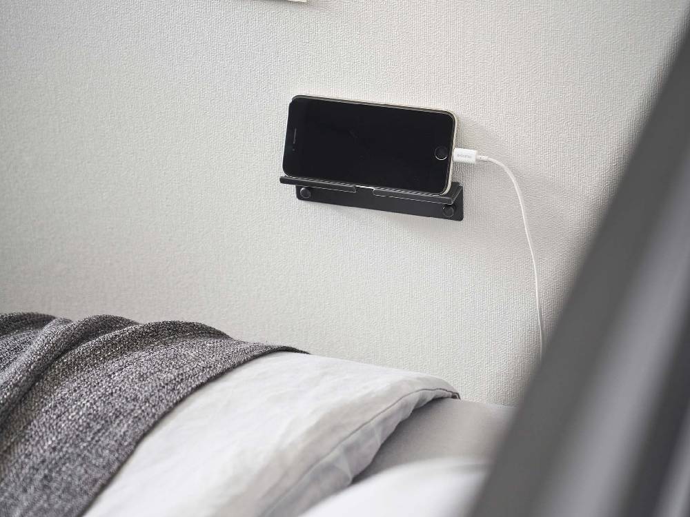 シルバー色のスチール製【tower/タワー】ウォールスマートフォンホルダーが壁にしっかりと取り付けられている様子