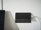 シルバーのスチール製ウォールスマートフォンホルダーが壁に取り付けられ、スマートフォンを安定して固定している様子