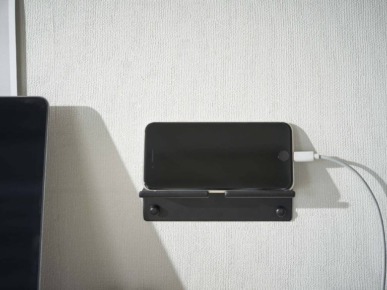 シルバーのスチール製ウォールスマートフォンホルダーが壁に取り付けられ、スマートフォンを安定して固定している様子