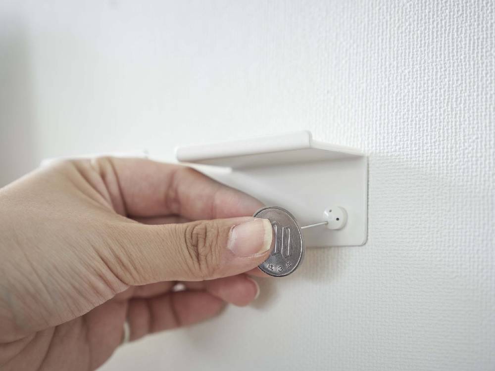 スチール製タワー型ウォールスマートフォンホルダーが壁の電源ソケットに取り付けられている様子