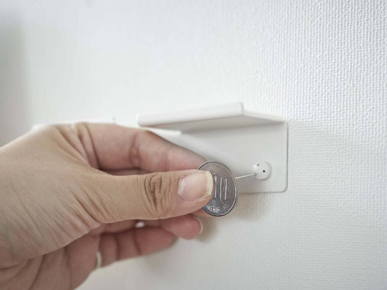 スチール製タワー型ウォールスマートフォンホルダーが壁の電源ソケットに取り付けられている様子