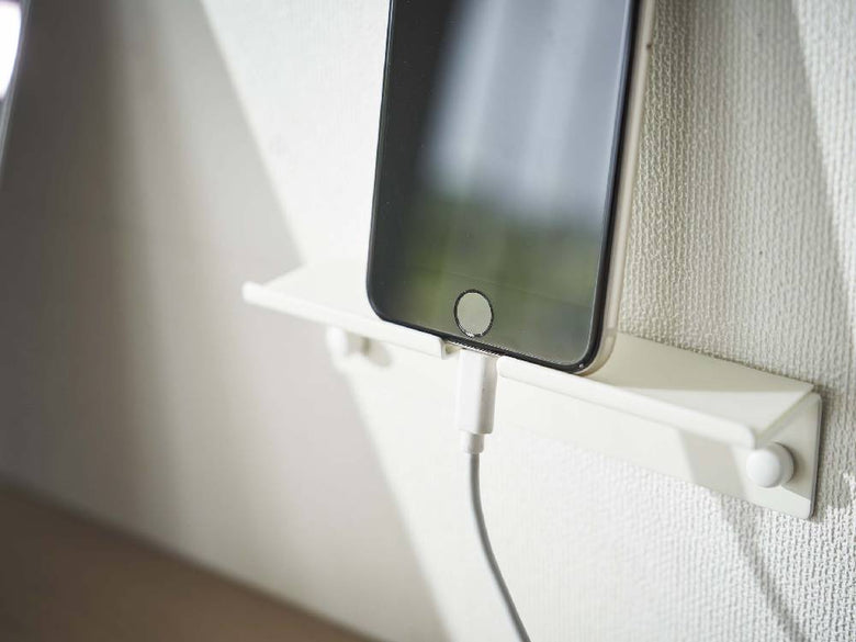 シルバー色の「tower/タワー」ウォールスマートフォンホルダーにスマートフォンが固定されている様子