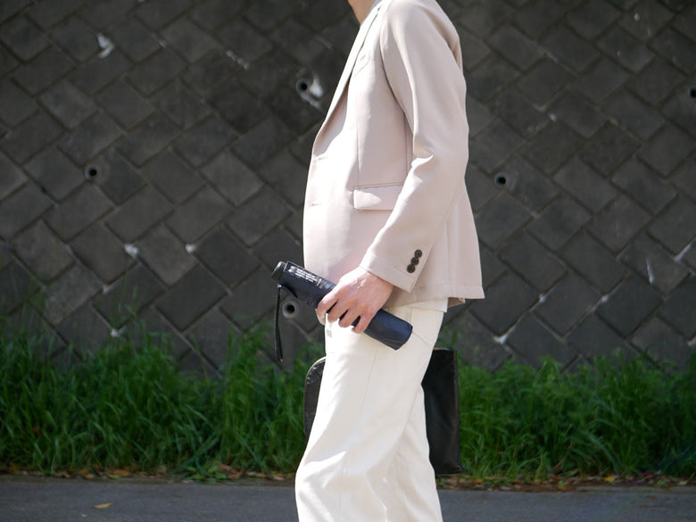 灰色のブレザーを着たフォーマルなパンツスーツ。襟や袖にボタンが付いており、ウエスト部分が際立っています。