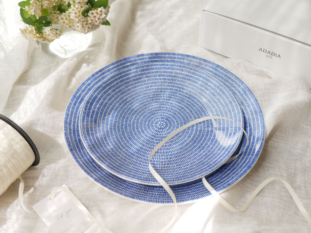 青色のアラビア24hアベックプレートとカトラリーがテーブルクロスの上に整然と並んだ食卓セッティング