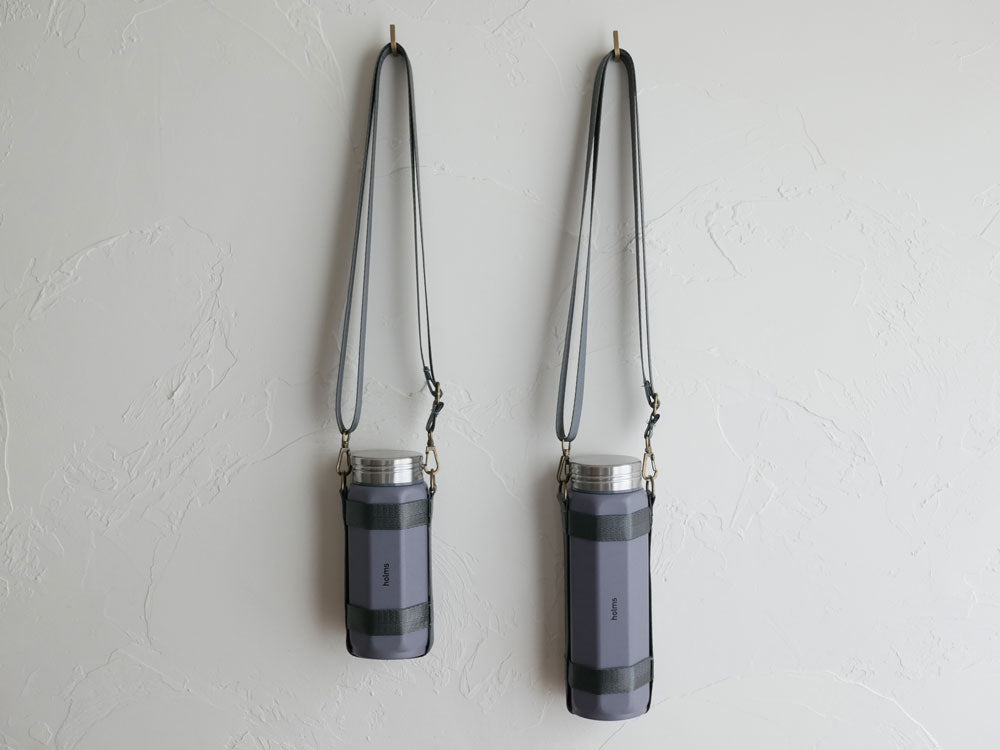 CB JAPANのholmsオクタボトル ロングショルダー、銀色のアルミニウムとプラスチック製シリンダー型水筒に長めのショルダーホルダー付き