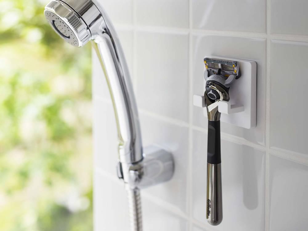 ミストのシェーバーホルダーが光沢のある壁面にフィルムフックで取り付けられており、複数のフックにシェーバーが掛かっている様子