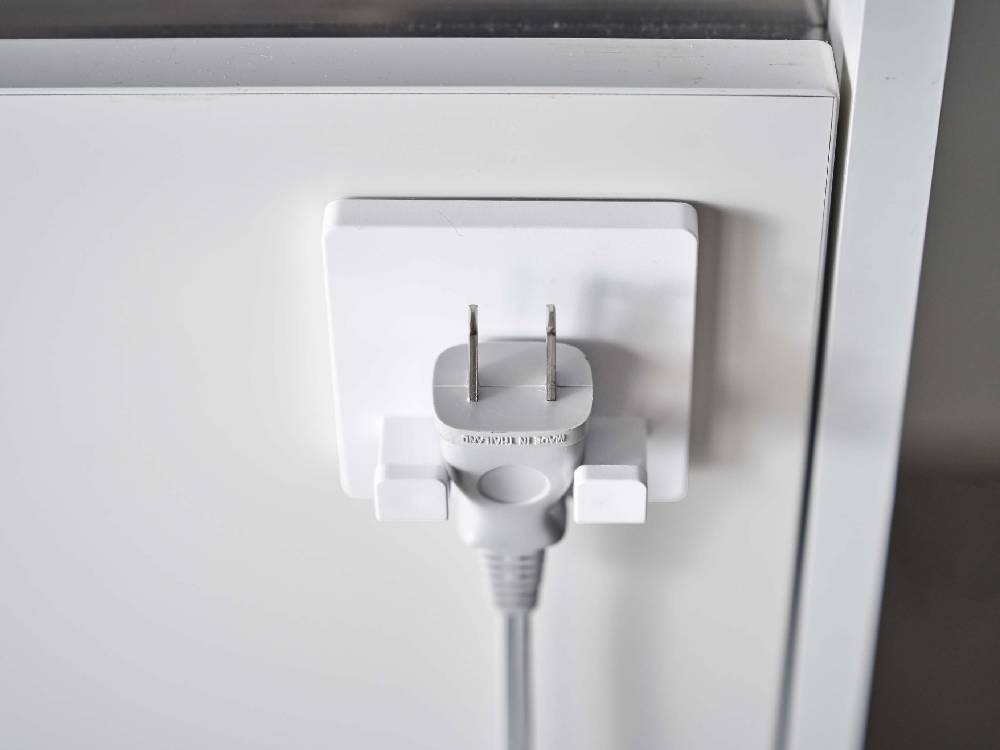 壁に取り付けられた【MIST/ミスト】フィルムフック シェーバーホルダーと電源プラグおよびケーブル