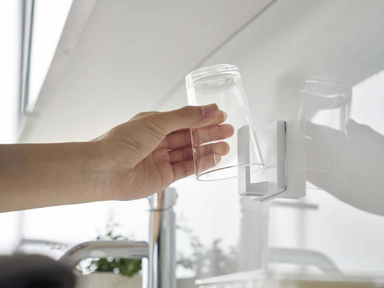 キッチンの壁に取り付けられた「MIST/ミスト フィルムフック タンブラーホルダー」にグラスが掛かっている様子