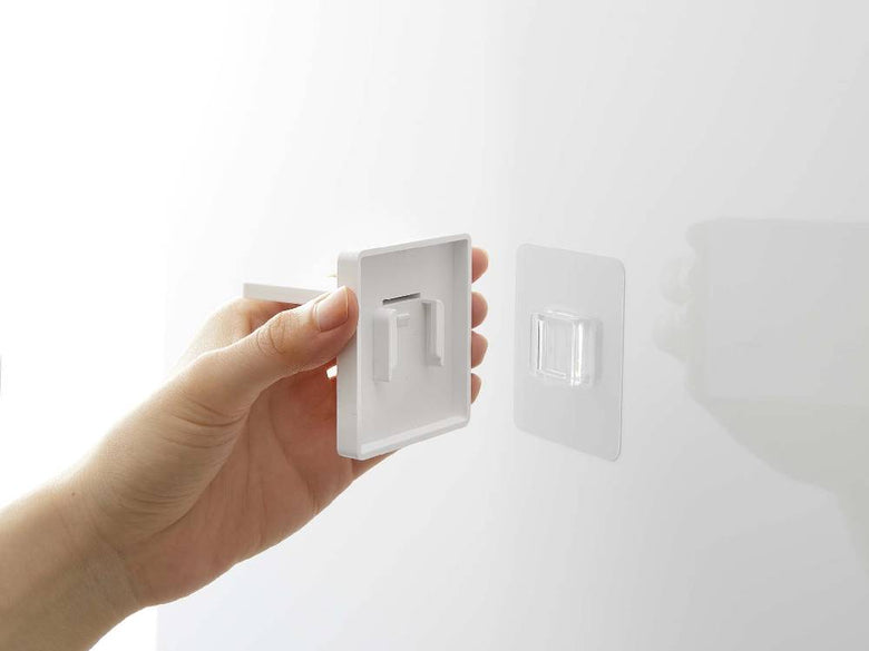 MISTのマグネットタンブラーがプラスチック製フィルムフックを使用して、壁のライトスイッチ近くに取り付けられている様子