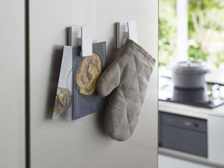 キッチンの壁に取り付けられたMISTフィルムフック ワイドクリップ2個組で、家庭用植物が掛けられている様子