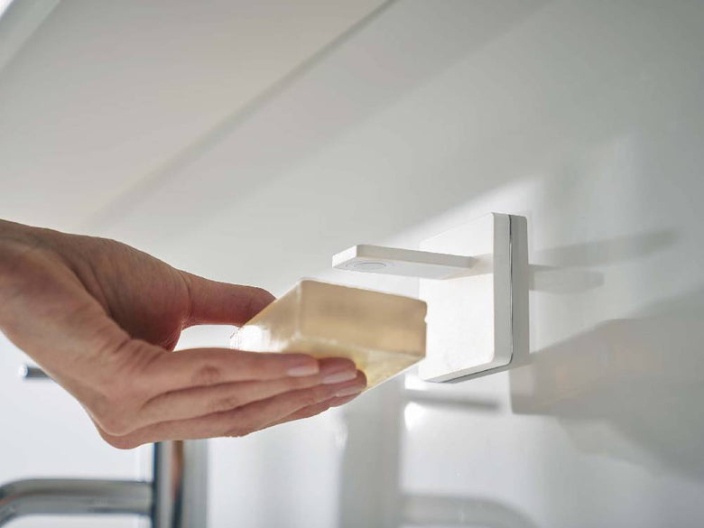 MIST/ミストのフィルムフック式マグネット石鹸ホルダーが光沢のあるタイル壁に取り付けられており、ABS樹脂とステンレス素材で作られたシンプルで耐久性のあるデザインが見える