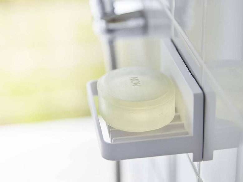 ガラスの棚に掛けられたプラスチック製の水が流れるソープトレー