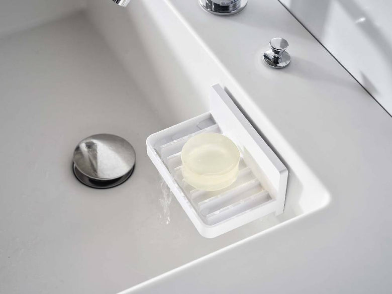 浴室用セラミックシンクに銀色のミストフィルムフックが取り付けられ、水が流れるソープトレーを備えた様子