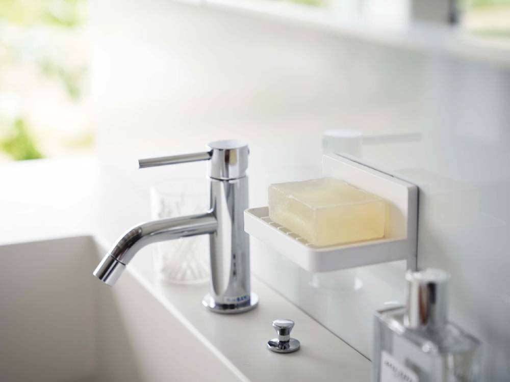 バスルームの洗面台にフィルムフックで取り付けられた「MIST/ミスト」水が流れるソープトレー。ABS樹脂製で実用的なデザイン