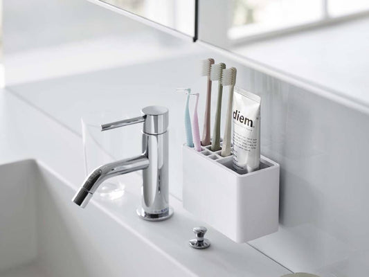 浴室の洗面台に取り付けられた[MIST/ミスト]フィルムフック歯ブラシスタンド。歯ブラシやソープディスペンサーを整理するプラスチック製のスタンド。